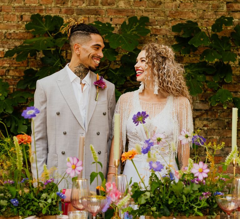 Bride and groom standing behind colourful wedding table decor and flowers at fiesta theme wedding