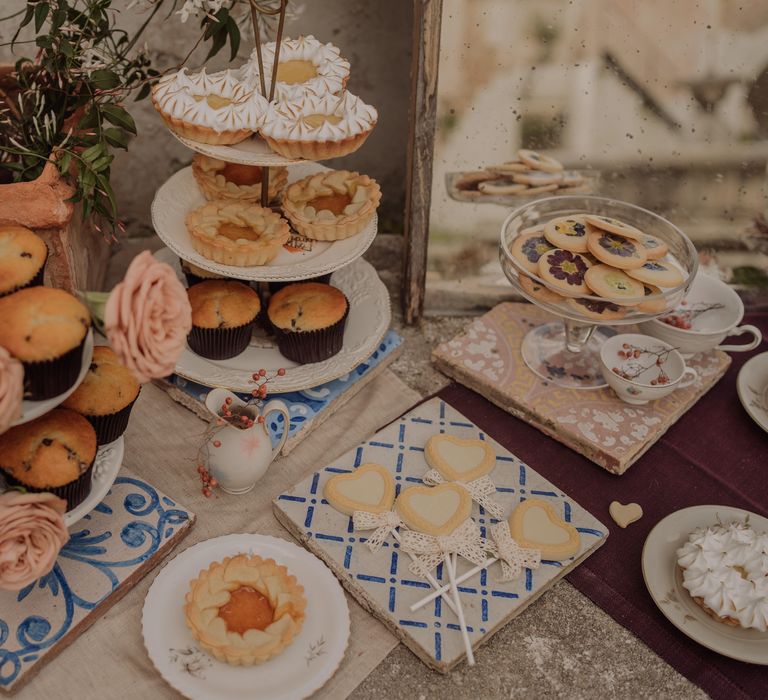 Buffet style dessert table with rustic vibe and hand painted coasters on stone table