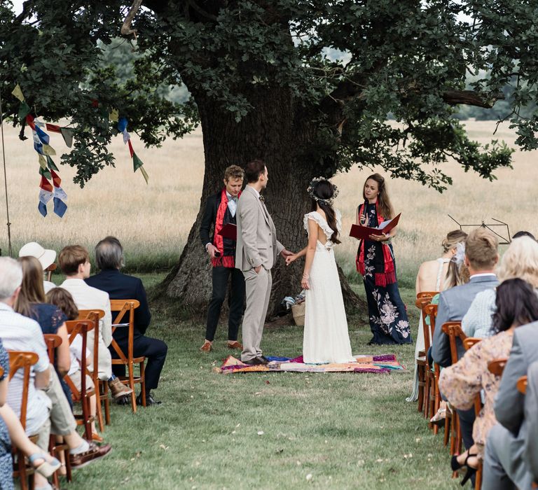 Bride & groom stand at the front of wedding guests during their outdoor wedding ceremony