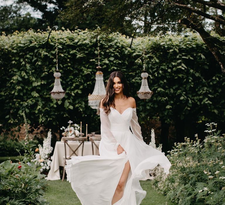 Bride in strapless Molly Suzanne Neville Nova collection wedding dress with sheer long sleeves and front slit 