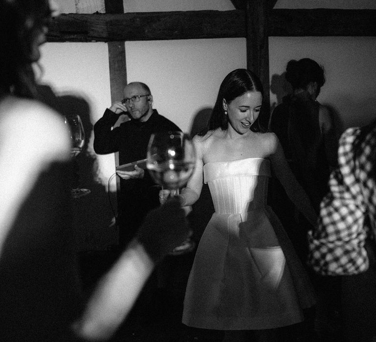 Bride in short Alex Perry A line dress dances during evening wedding reception at Loseley Park in Surrey