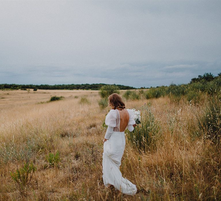 Bride walks through golden fields on her wedding day