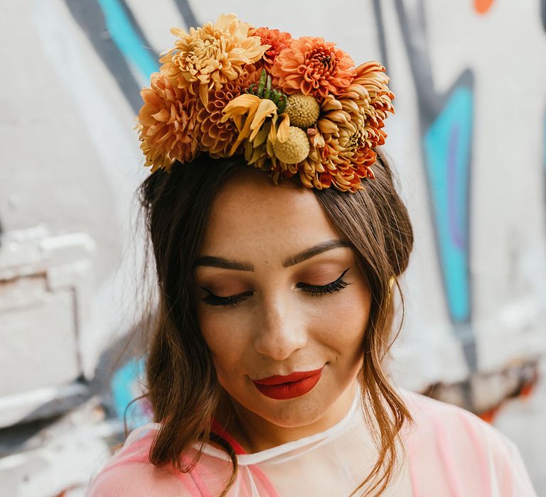 Beautiful bride in a cape veil with winged eyeliner and red lipstick makeup wearing a yellow flower crown 