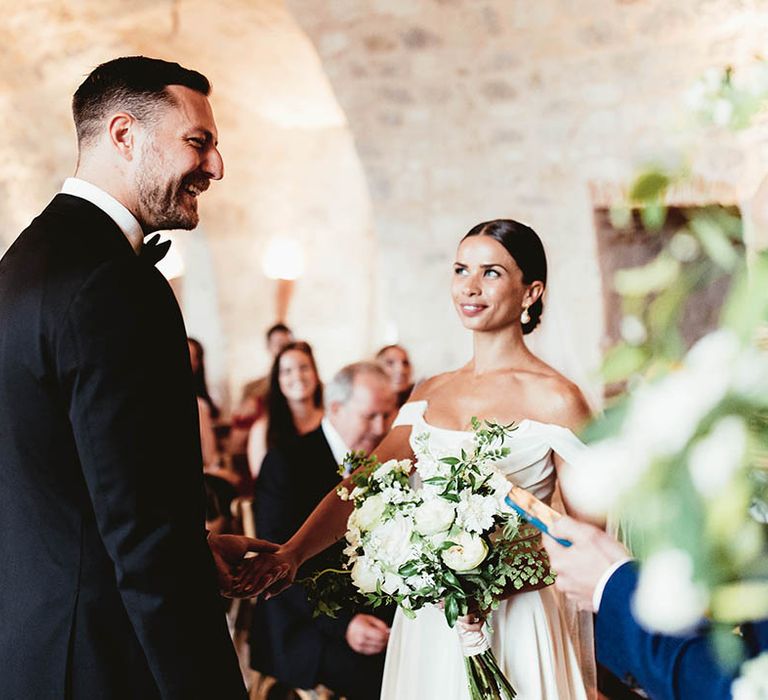 Bride looks lovingly at her groom as she wears her dark hair slicked back into low bun