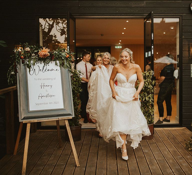 Bride in strapless wedding dress leads wedding guests outside