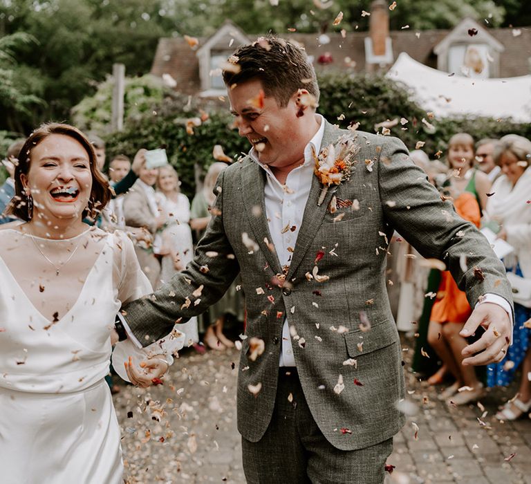 Fun confetti portrait with bride in a long sleeve wedding dress and groom in a grey check suit