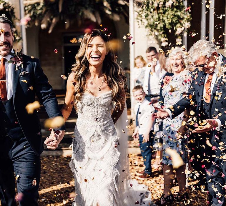 Bride & groom walk outdoors on their wedding day whilst holding hands