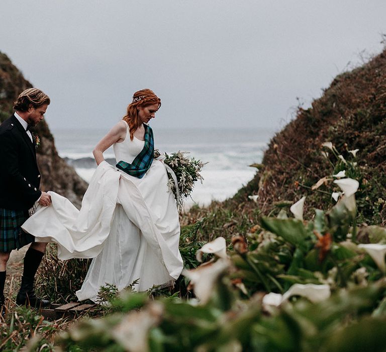 Groom in highland wear belong his bride in an a-line wedding dress up the Big Sur mountain 