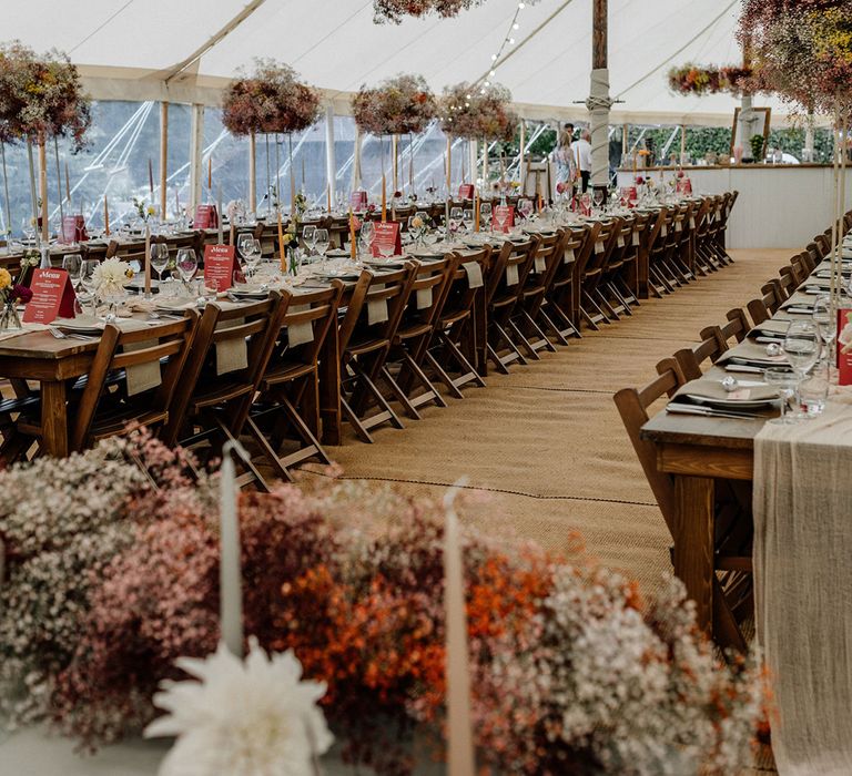 Stylish marquee wedding reception with hanging gypsophila flower clouds and tall centrepiece decor 