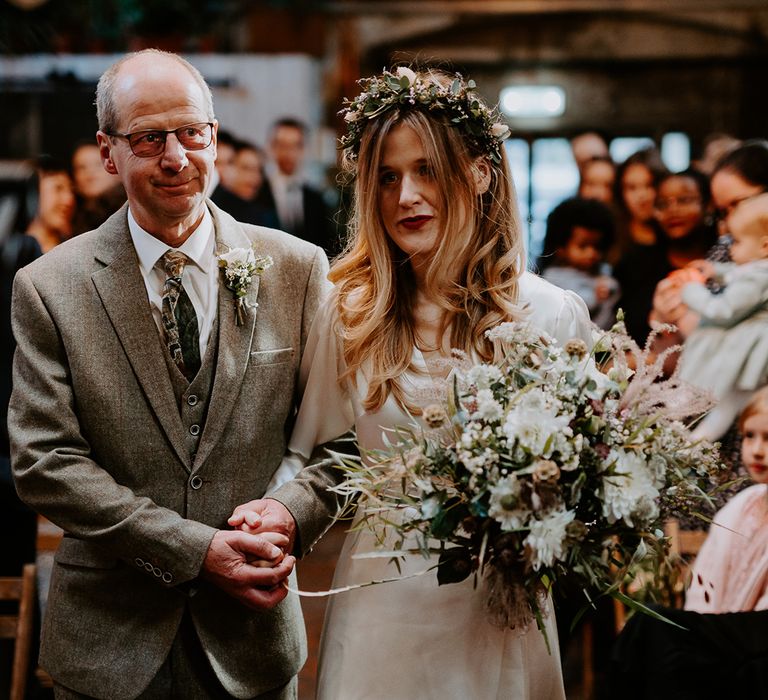 Bride walks down the aisle with her father on her wedding day 