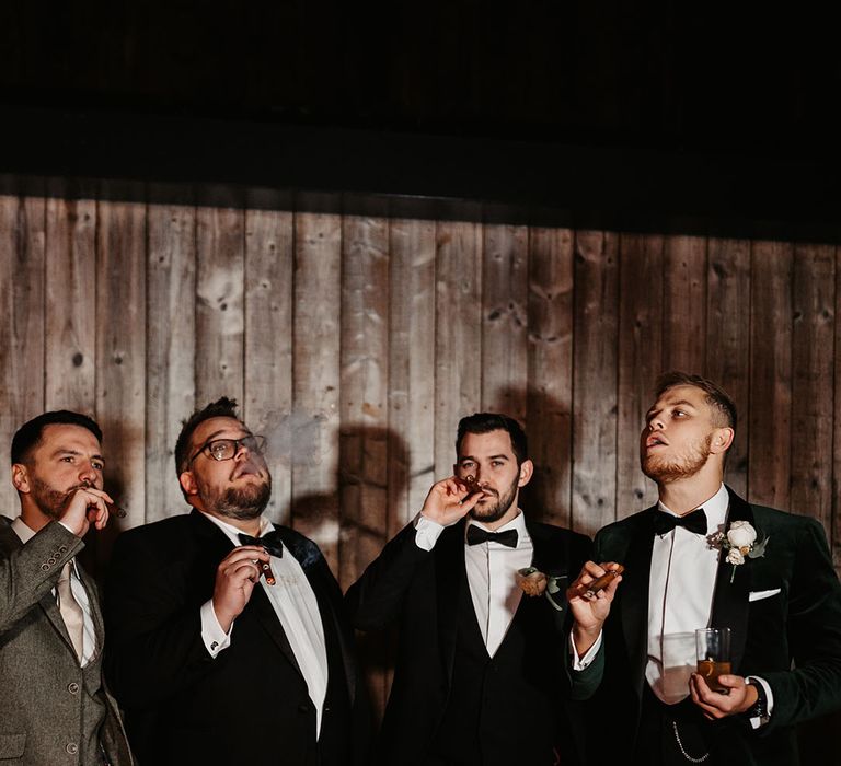 Groomsman take a puff from their cigars after winter wedding in the Lake District 