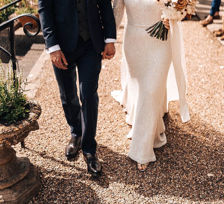 Groom in dark blue suit with paisley tie and dried flower boutonnière with bride in beaded vintage silhouette wedding dress