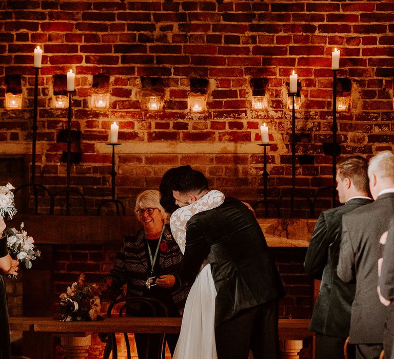 Groom in black velvet jacket hugs the bride as they become husband and wife