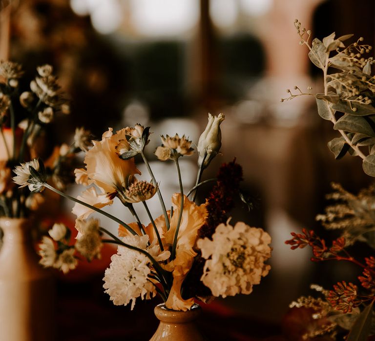 Small arrangement of flowers in warm toned vases for table decor 