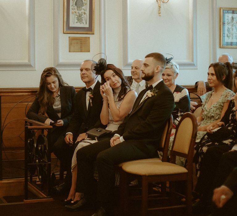 Wedding guests watch the ceremony and wipe their eyes as they get emotional