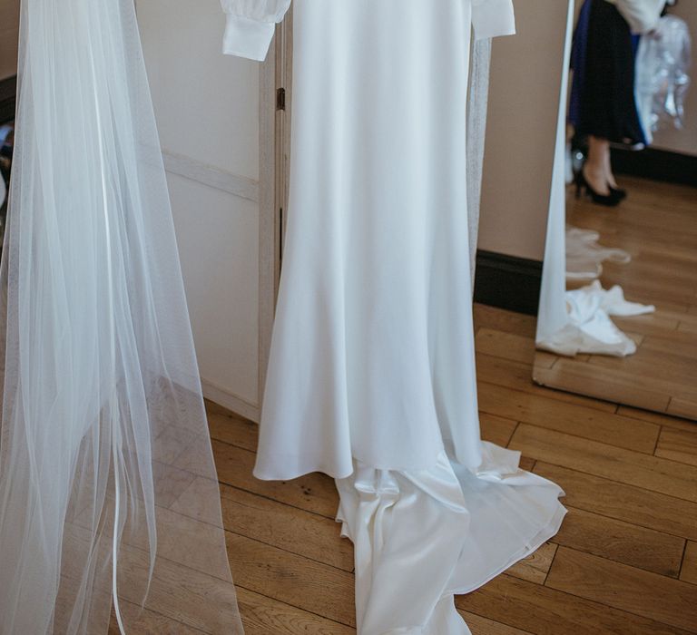 Suzanne Neville wedding dress with custom sheer sleeves and long veil hanging for bride