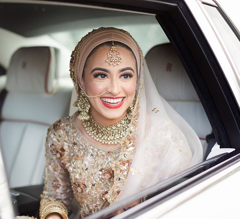 Bride wears red lipstick and smiles on her wedding day in wedding car 