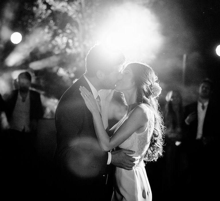 Bride & groom kiss outdoors as light shines behind them in Tuscany 