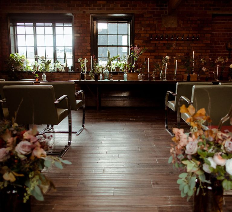 The Chimney House wedding venue complete with Autumnal floral bouquets lining the aisle and industrial brick wall styling 