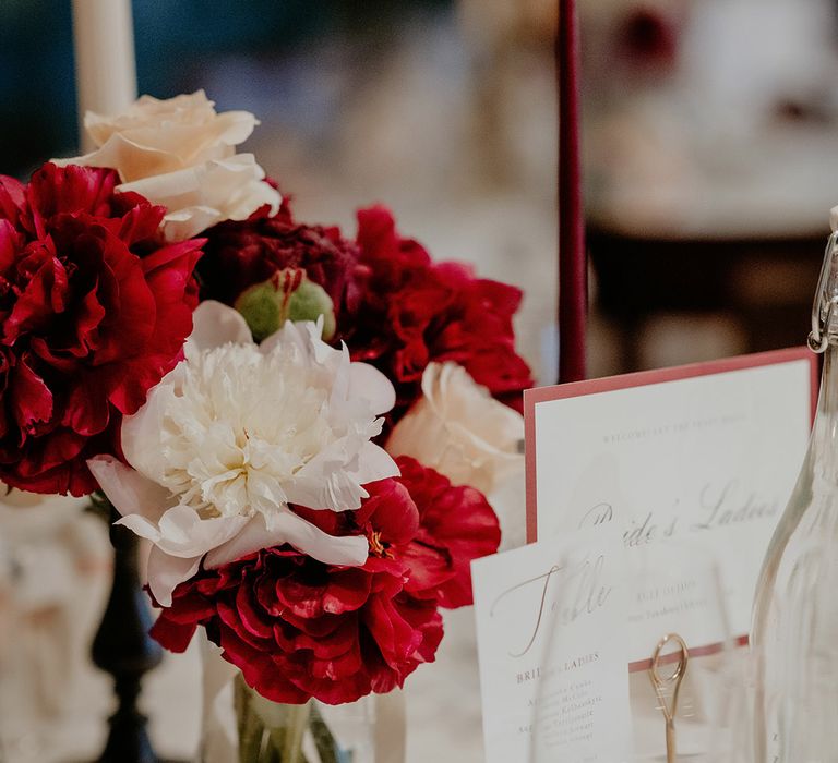 Red and white flowers decorate the tables with gold decor 