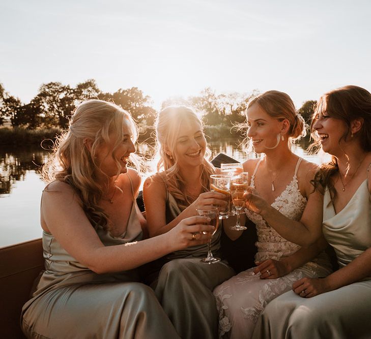 Bride sits with her bridesmaids in satin bridesmaid dresses as the sun begins to set across the Thames