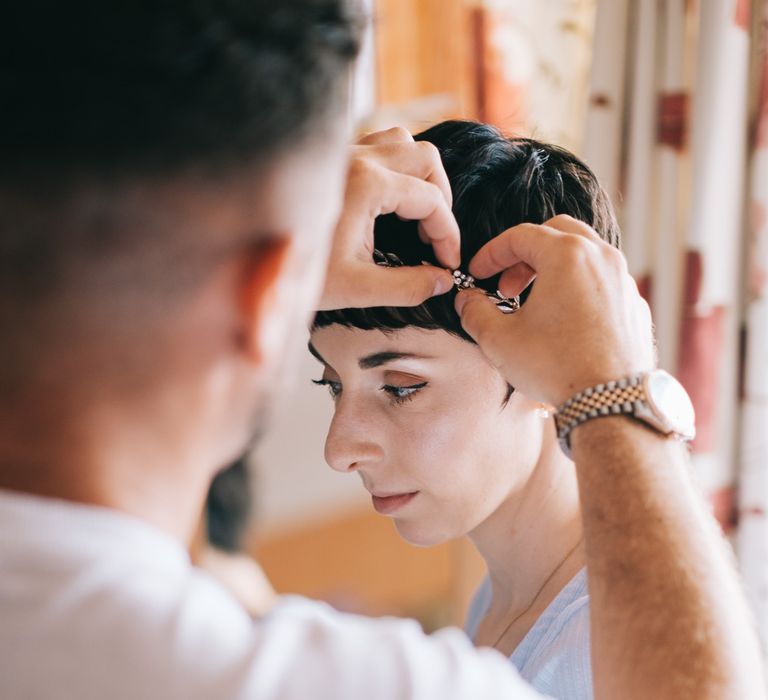 Bride wears her dark hair in a pixie cut and has bridal crown added on her wedding day