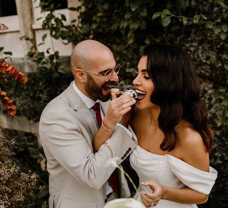 Bride and groom feed themselves some cake at their wedding 