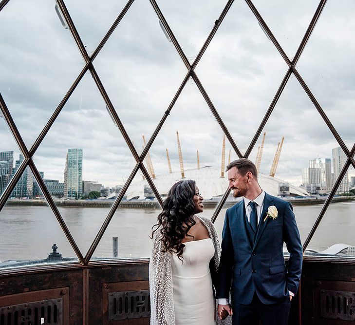 Bride & groom stand at the top of lighthouse on their wedding day for couples portraits 