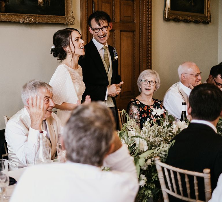 Bride and groom laughing and chatting with wedding guests in reception room of Kelmarsh Hall country house wedding venue