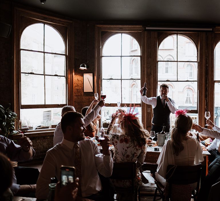 Wedding guests listen to speeches at pub reception after Hackney Town Hall 