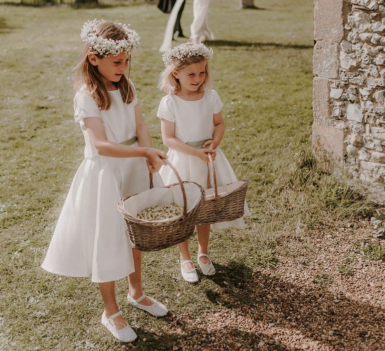 Flower girls in white dresses in white flower crowns and bouquets made from gypsophila 