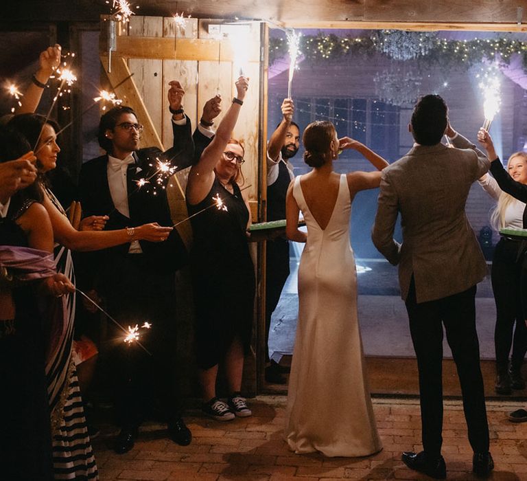 Bride & groom walk through sparkler exit into reception venue 