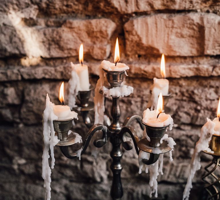 Rustic silver candelabra with lit melted white candles 