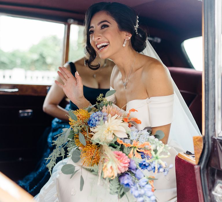 Bride holds colourful bridal bouquet and wears her hair pinned back with peal hair accessory 