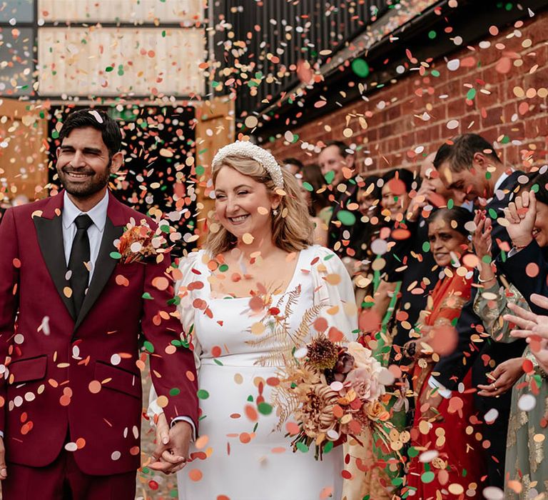 Colourful green, red, orange, white wedding confetti moment as the bride and groom exit their humanist wedding ceremony 