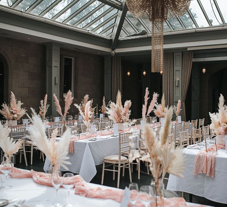 Hampton Manor wedding venue with tables with white tablecloths, pink table runners and white and pink pampas grass centrepiece decor 