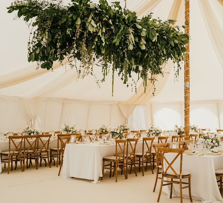 Hanging foliage installations above banquet tables with classic styling for marquee wedding 