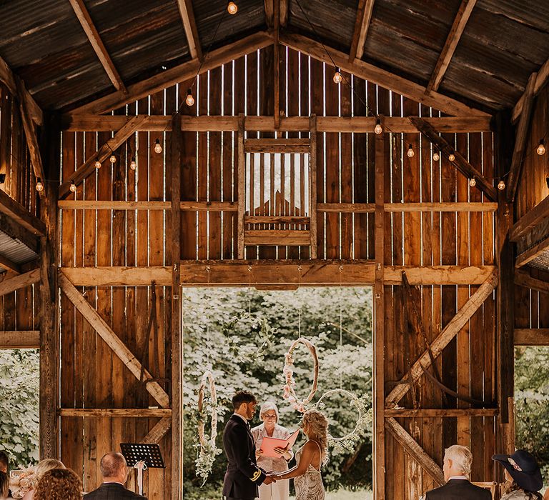 Nancarrow Farm Cornwall rustic barn wedding venue decorated with hula hoop decor and the bride and groom standing at the altar for boho wedding 