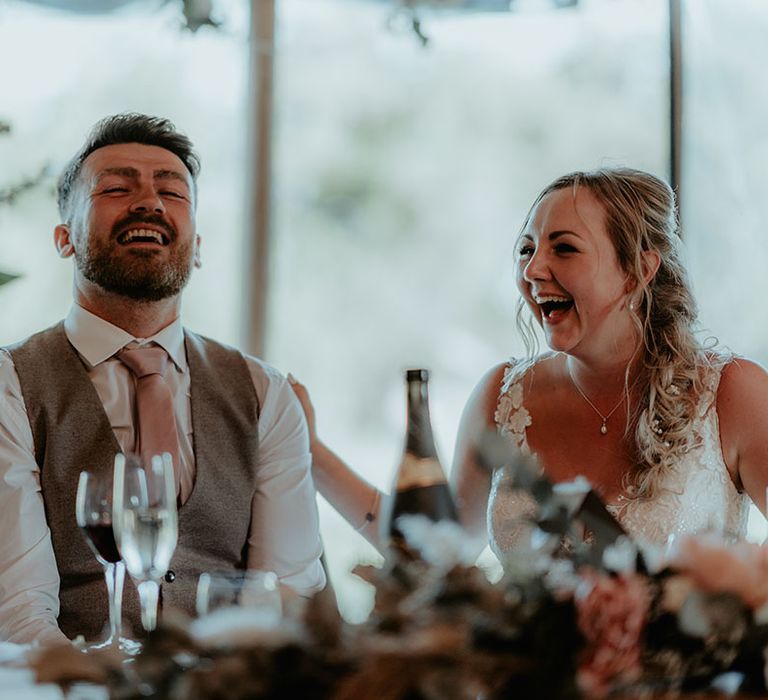 Bride & groom laugh during tipi wedding speeches 