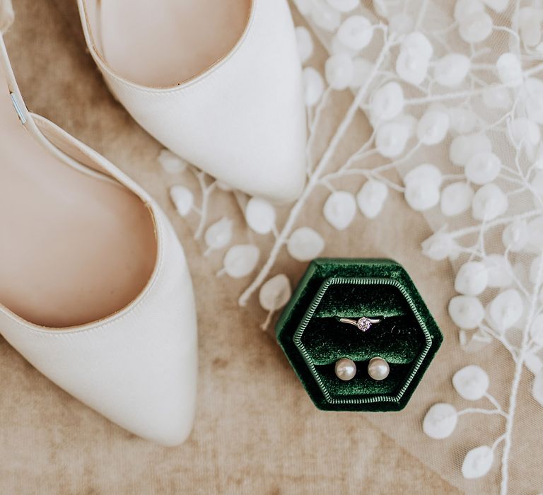 White simple Harriet Wilde wedding shoes with the bride's patterned veil and dark green velvet hexagonal ring box with diamond engagement ring and pearl stud earrings