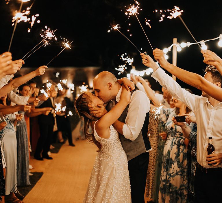 Traditional sparkler send-off for a rustic luxe wedding with the bride and groom sharing a kiss 