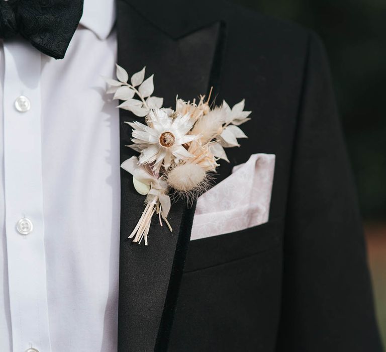 Traditional and classic black tie suit worn by groom with white pampas grass buttonhole 