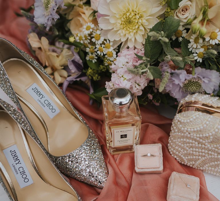 Sparkly pointed Jimmy Choo wedding shoes with Jo Malone perfume with the pastel flower bridal bouquet and pearl clutch with jewellery 