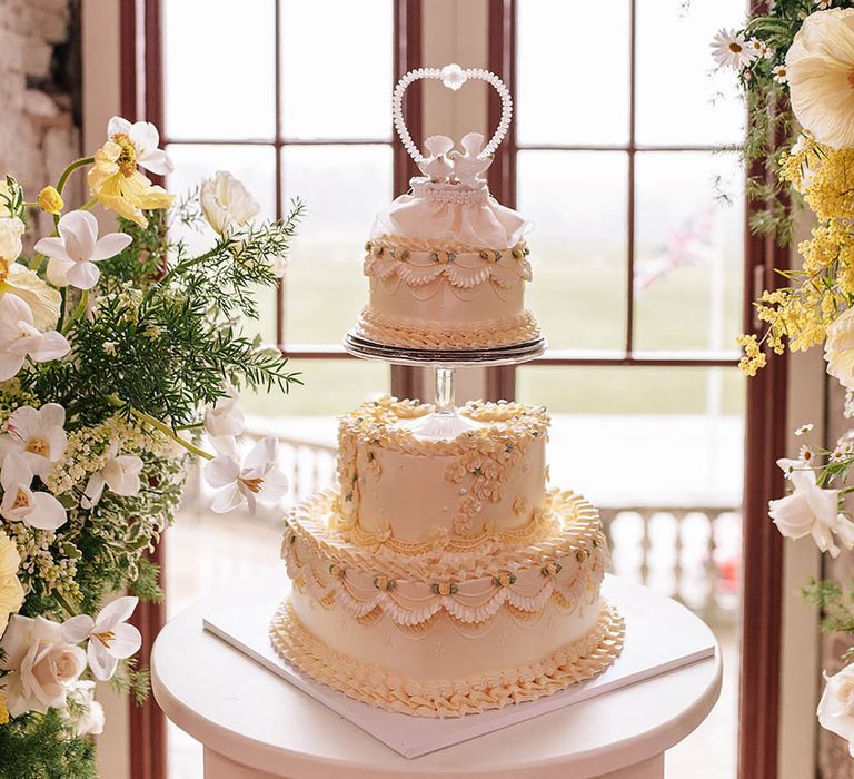 Epic three tier retro wedding cake with pastel yellow and white frosting with vintage dove cake topper 