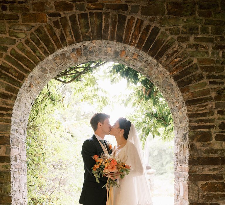 Bride wearing delicate lace wedding veil with the groom in a navy suit for country house wedding at Coombe Trenchard 