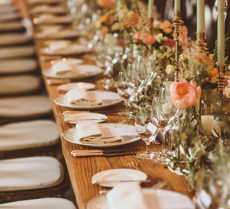 Grey and white patterned plates with white napkins, cutlery and glassware with pink flower decorations 