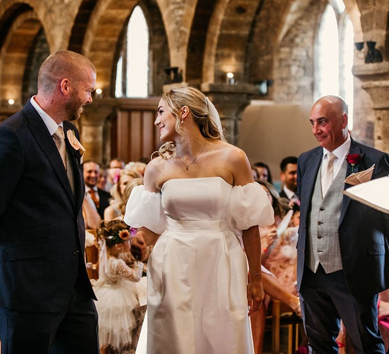 Father of the bride watches the bride greet the groom at the end of the aisle 