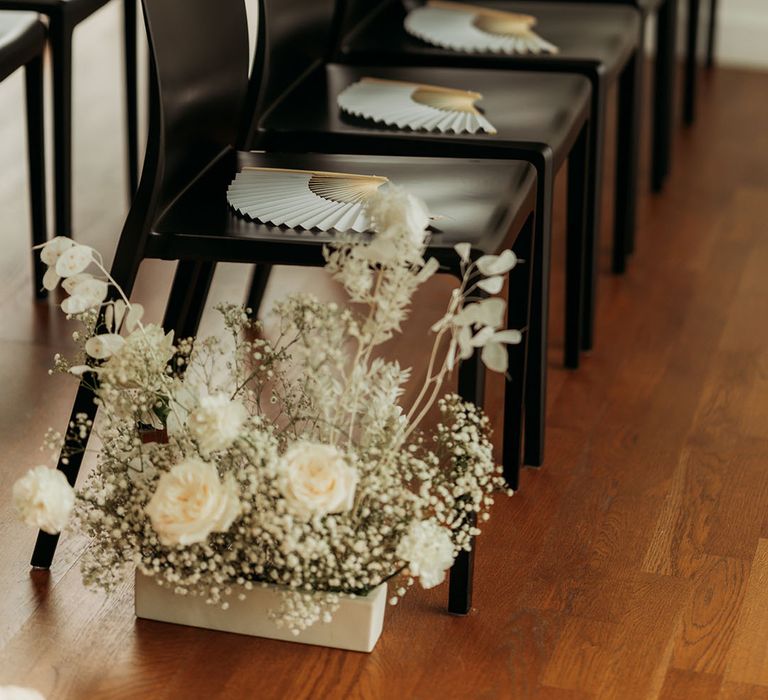 White rose and gypsophila wedding aisle decor with fan wedding favours 