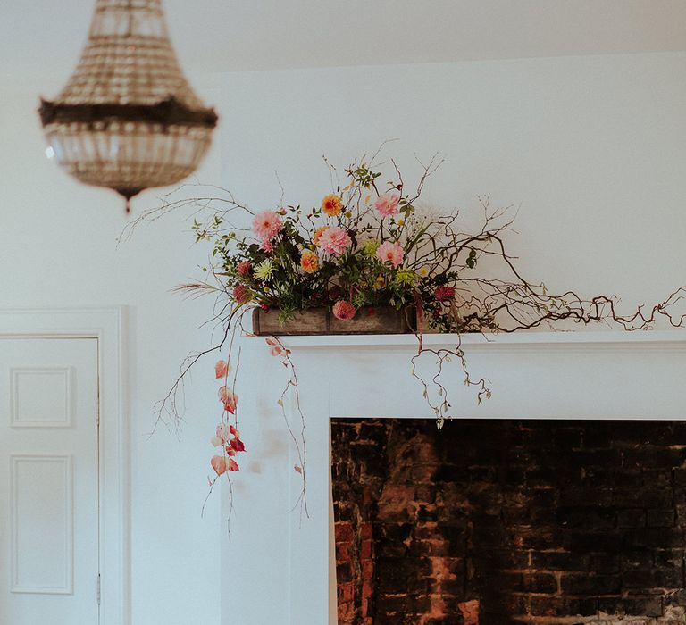 Pillar candles in white fireplace with pink flower decorations to match the theme 