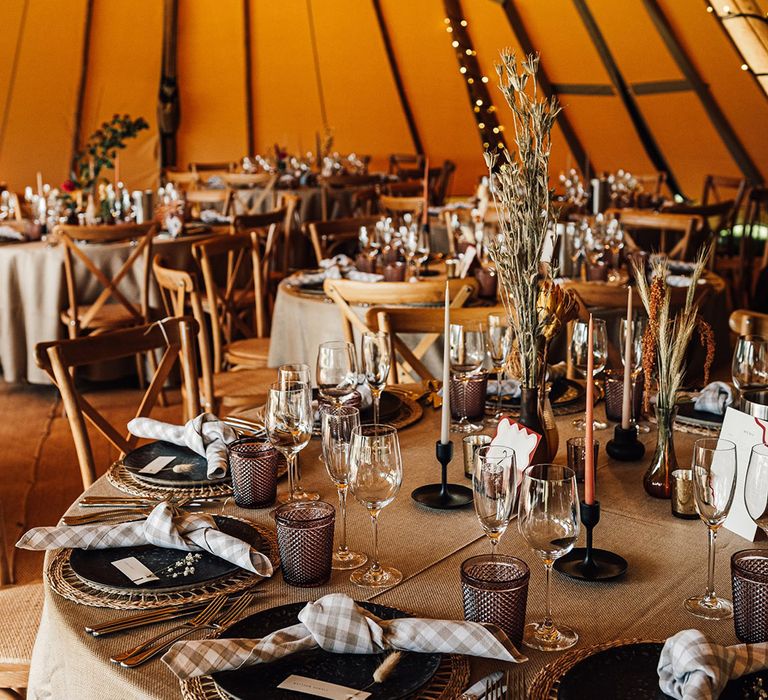 Tipi wedding with neutral toned tablescape including neutral candles, napkin and decor 